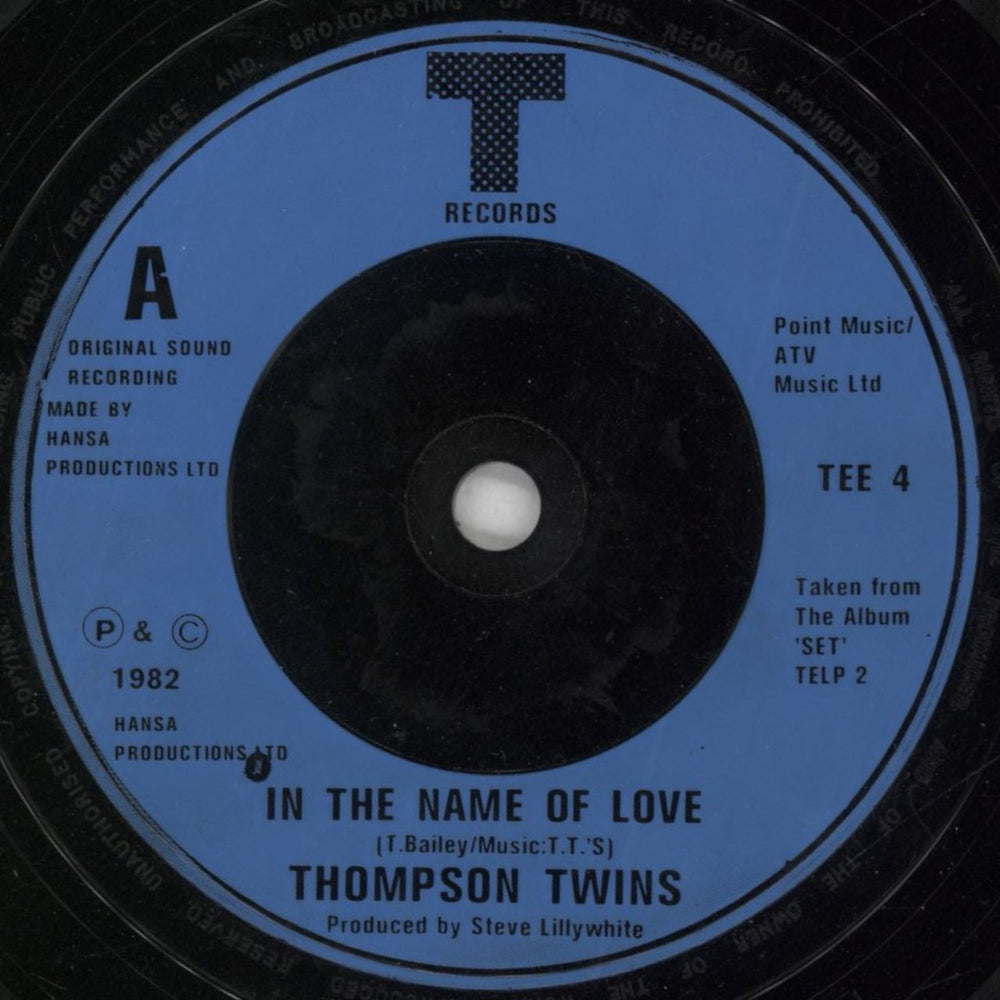 Thompson Twins In The Name Of Love + Sleeve UK 7" vinyl single (7 inch record / 45) TWI07IN856041
